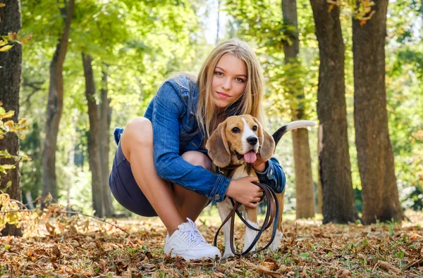 Pretty blond flicka sitta kramar Beagle hund — Stockfoto