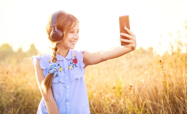 Dospívající dívka se sluchátky s roztomilý selfie — Stock fotografie