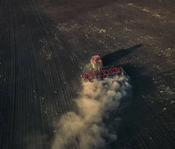 Воздушный обзор красного трактора вспахивает землю — стоковое фото