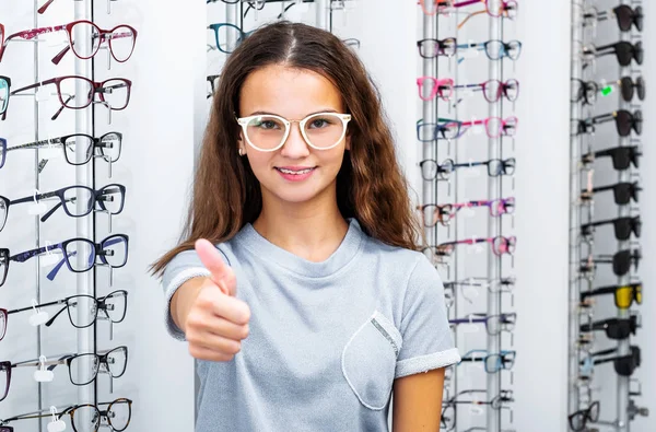 Genç kız optik mağazada ayakta başparmak alarak — Stok fotoğraf