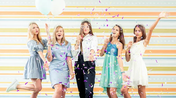 Bastante niñas adolescentes sonrientes en vestidos alegremente levantaron las manos juntos y ejecutar slappers con destellos en la fiesta de cumpleaños —  Fotos de Stock