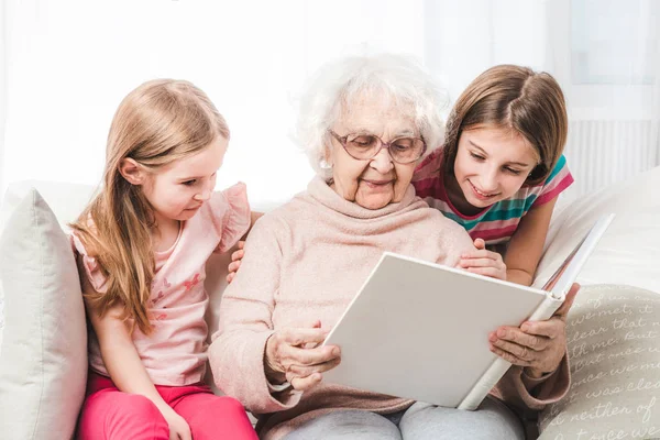 Abuela con nietas leyendo libro — Foto de Stock