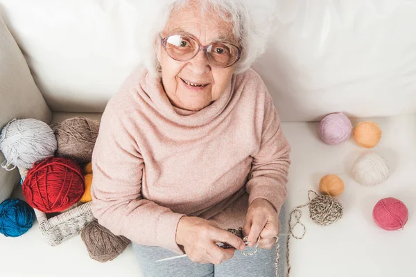 Mujer anciana sonriente tejiendo — Foto de Stock