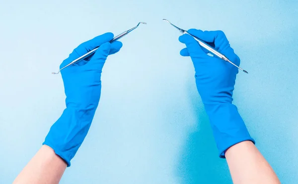 Manos en guantes azules sosteniendo herramientas dentales — Foto de Stock