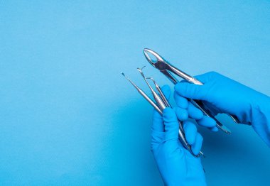 Diş kelepçeleri ve ameliyat çubukları tutan mavi eldiven eller