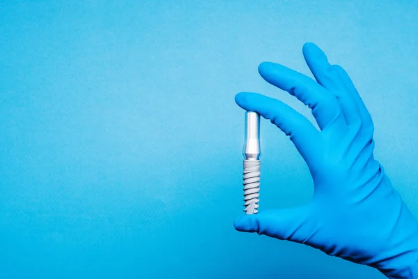 手在蓝色手套举行植入物牙科工具 — 图库照片