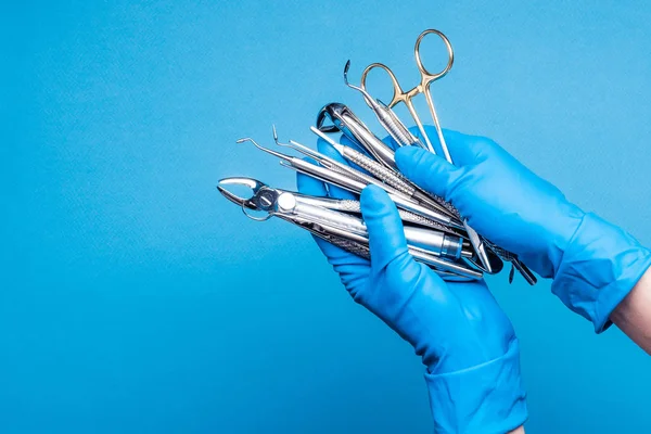 Handen in blauw handschoenen holding tandheelkundige apparatuur en metalen instrumenten — Stockfoto
