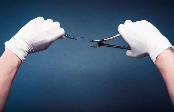 Hands in gloves holding surgery dental tools — Stock Photo, Image