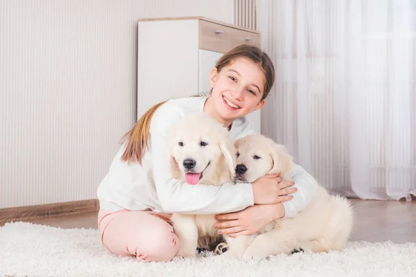 Tiener meisje zitten knuffelen retriever puppies — Stockfoto