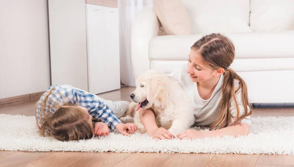 Systrar som ligger tillsammans med söta Retriever valp — Stockfoto