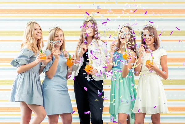 Красивые улыбающиеся девочки-подростки в платьях и коронах, держащие напитки вместе — стоковое фото