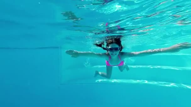 Улыбающаяся девушка плавает под водой в бассейне — стоковое видео