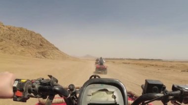 Çölde dörtlü bisiklet sürüyor.