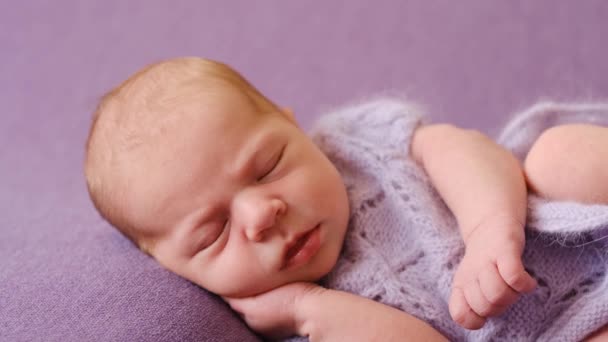 Новорожденный на фиолетовом одеяле в трикотажной одежде — стоковое видео
