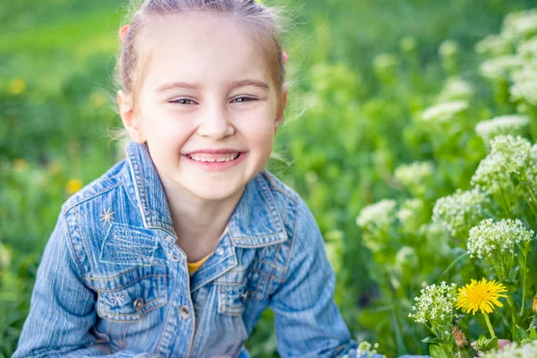 Маленька усміхнена дівчинка сидить у полі трави — стокове фото