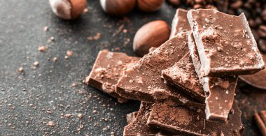 Siyah bir masada çikolata ve fındık.