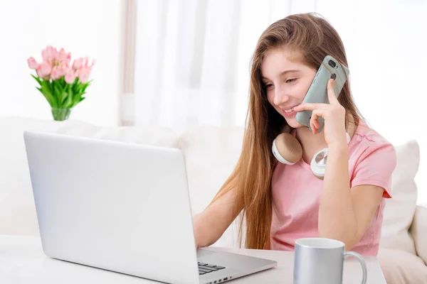 Girl phoning in front of laptop — Stock Photo, Image
