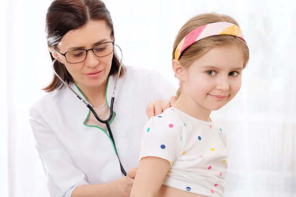 Doktorn lyssnar på flicka med stetoskop — Stockfoto
