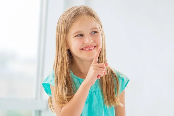 Niña con bonita sonrisa mostrando el dedo índice — Foto de Stock