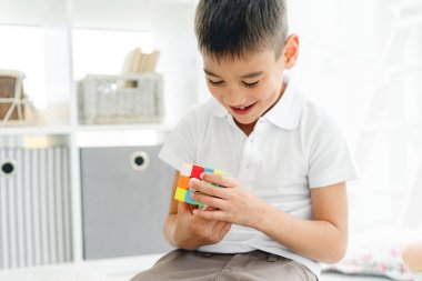 Parlak oyun odasında zeka küpünü çözen küçük mutlu çocuk.