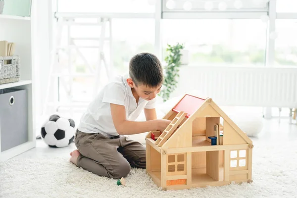 Niedlicher kleiner Junge spielt mit Puppenhaus — Stockfoto