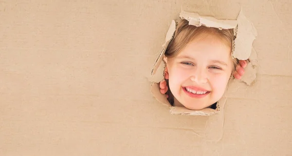 Klein meisje op zoek recht uit kartonnen doos — Stockfoto