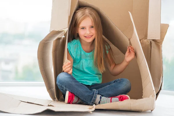 Klein kind meisje zitten in kartonnen huis — Stockfoto