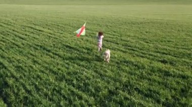 Küçük kız sahada uçurtma uçuruyor.