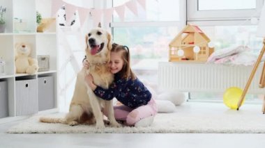 Mutlu küçük kız sevimli köpeğe sarılıyor.