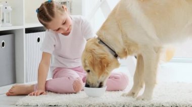 Mutlu küçük kız tatlı köpeği besliyor.
