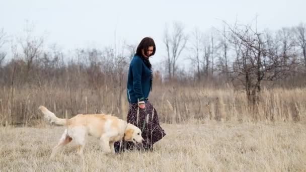 Женщина выгуливает собаку на природе — стоковое видео