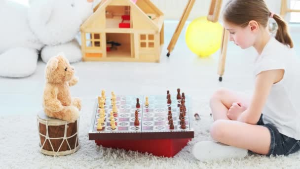 Маленька дівчинка грає в шахи з Тедді — стокове відео