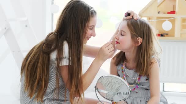 Chica bonita pintando labios de hermana pequeña — Vídeo de stock
