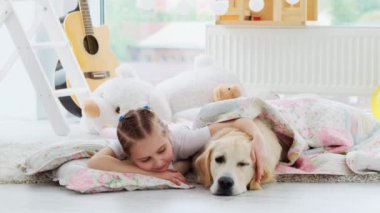 Küçük kız ve köpek yastıkta yatıyor