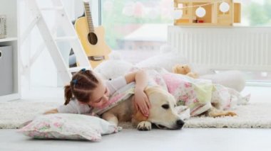 Küçük kız ve köpek yastıkta yatıyor