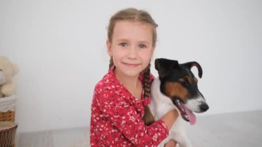 Küçük kız tilki teriyer köpeğine sarılıyor.