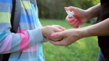 Kız ellerine dezenfektan sıkan kadın.