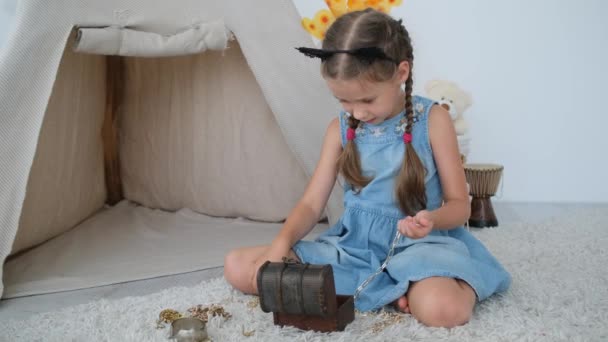 Маленька дівчинка грає зі скарбницею — стокове відео