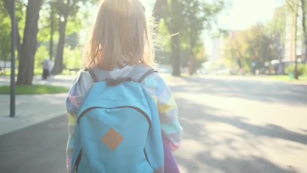 Liten flicka som går till skolan genom parken — Stockvideo