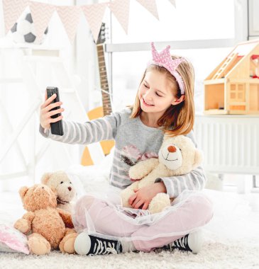 Kız oyuncak ayıyla selfie çekiyor.