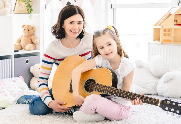 Mother with daughter playing guitar