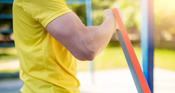 Muscular arm with elastic rubber band — Stock Photo, Image