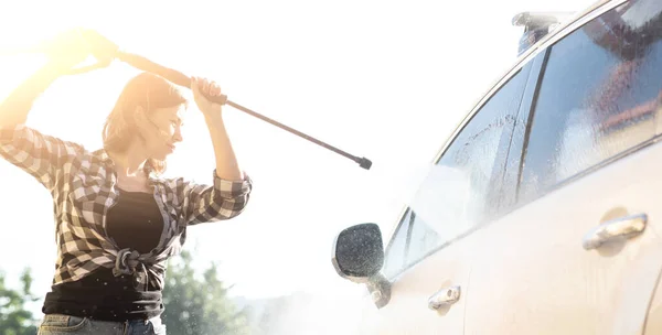 Woman cleaning car window with water — Stock Photo, Image