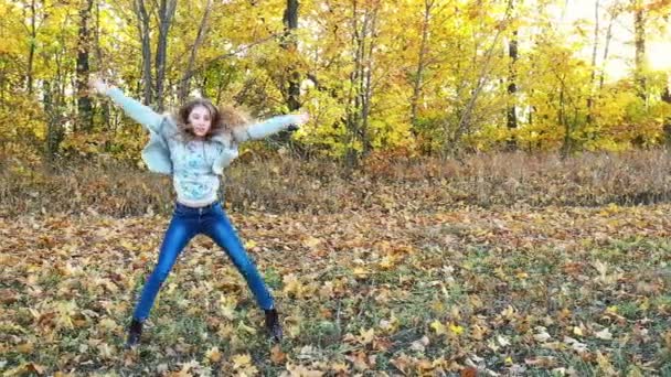 Linda menina está dançando sozinha entre folhas de bordo caídas — Vídeo de Stock