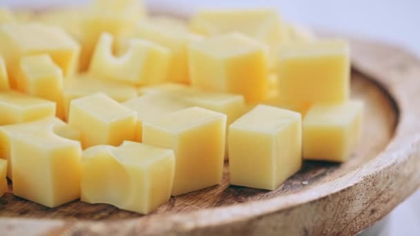 Kostkovaný sýr se otáčí na dřevěné desce — Stock video