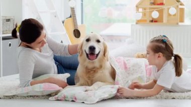 Anne ve kızı, köpekleri yatağa yatırıyor.