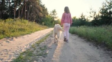 Küçük kız köpekle yürüyor.