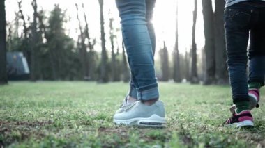 Anne ve iki kızı el ele tutuşup çimenlerde geziniyorlar..