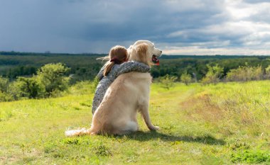 Güzel küçük kız sadık köpeğe sarılıyor.