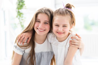 Sevimli gülümseyen kız kardeşler kucaklaşır